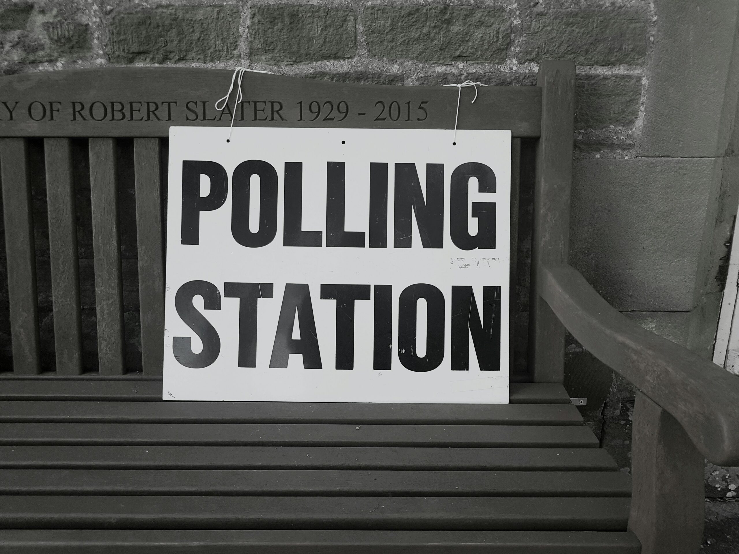 White sign on a bench that reads "POLLING STATION".